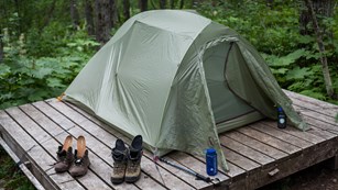 a tent on a wooden platform in the forest