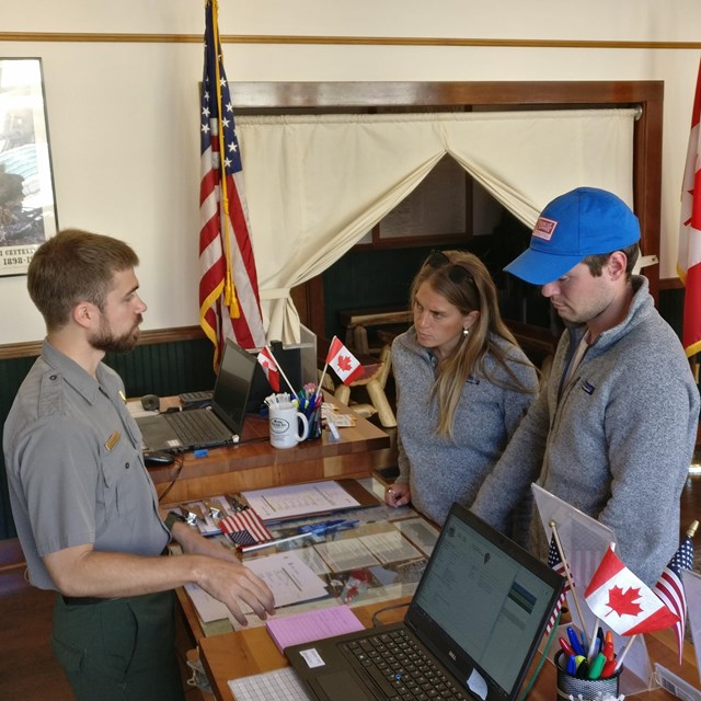 A ranger talks to two people at a desk