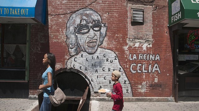 Mural of Celia Cruz on a brick wall with words saying La-Reina Celia