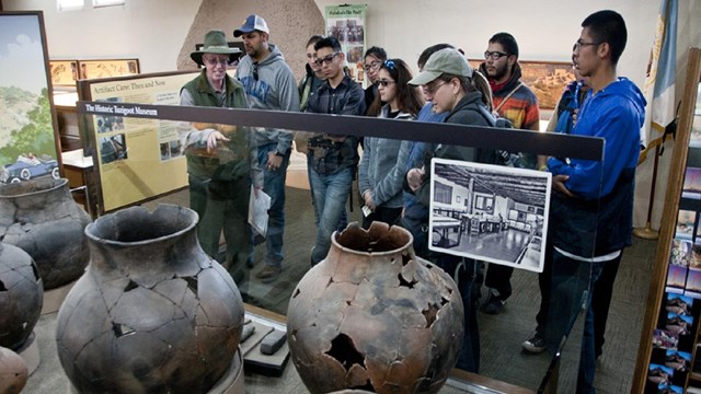 Students and park ranger look over a museum exhibit