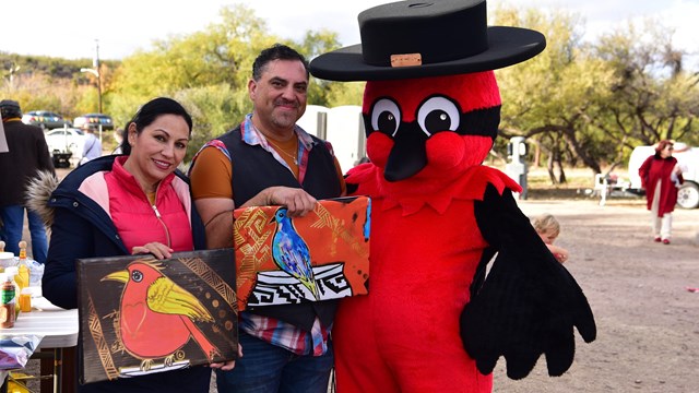Pancho (the Vermiliion Flycatcher mascot) and visitors with artwork of birds