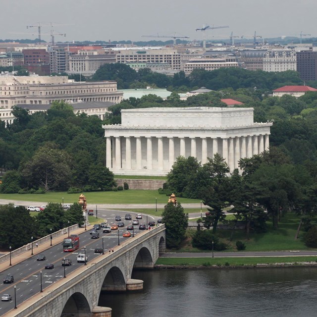 A bridge with cars connects to a large traffic circle around the Lincoln Memorial.