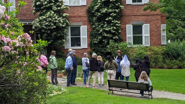 A tour group stands outside a historic mansion