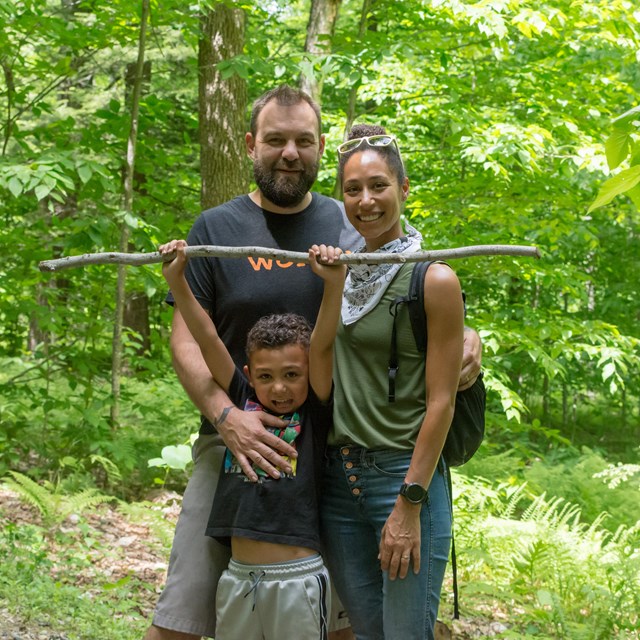 Two adults and a child pose for a photo on a trail
