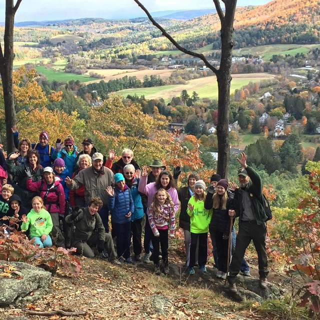 Group of hikers on top of mountain with view of Woodstock behind them