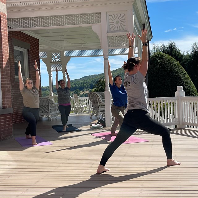 Yoga practice takes place with three people on mansion porch