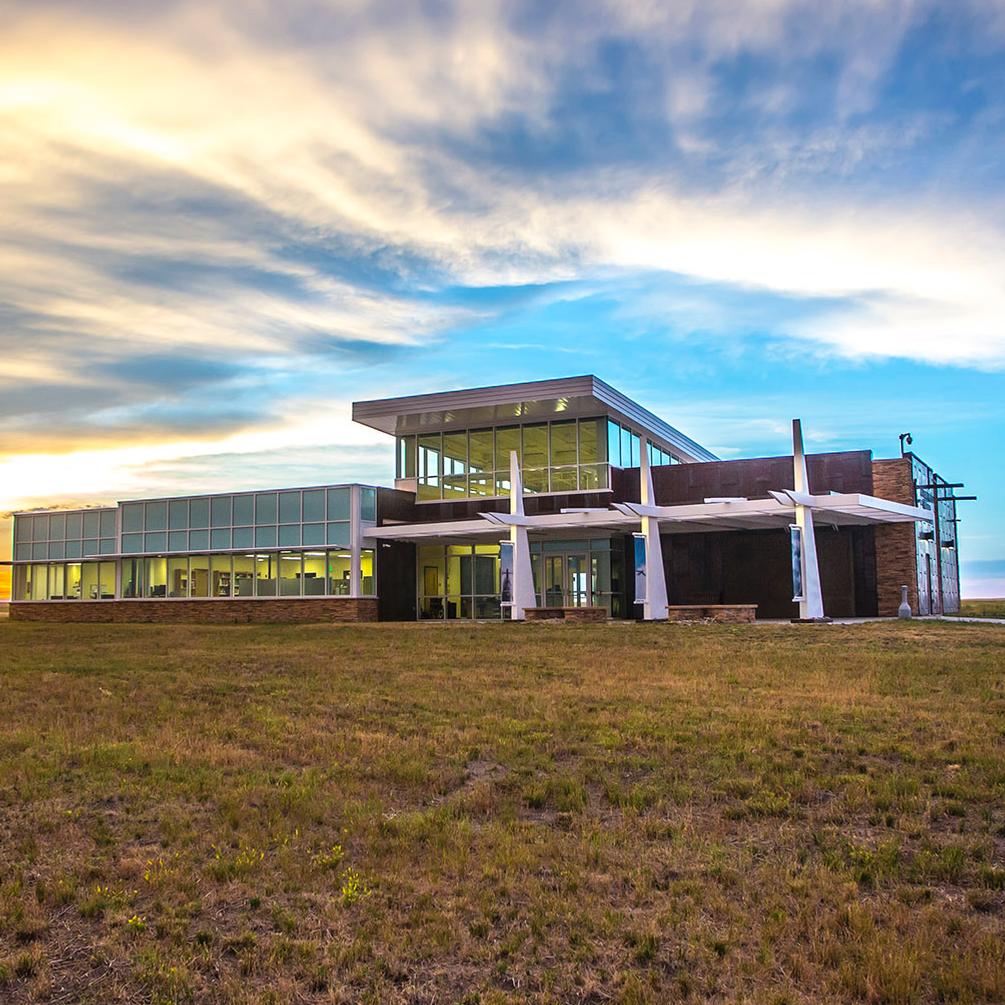 A concrete walk leads to a glass and steel building