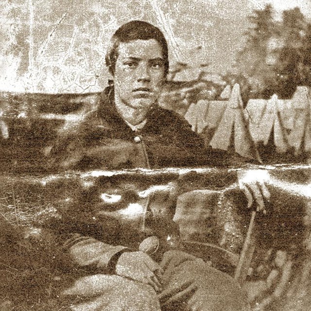 A young, white man sits for a portrait in a Union military uniform.