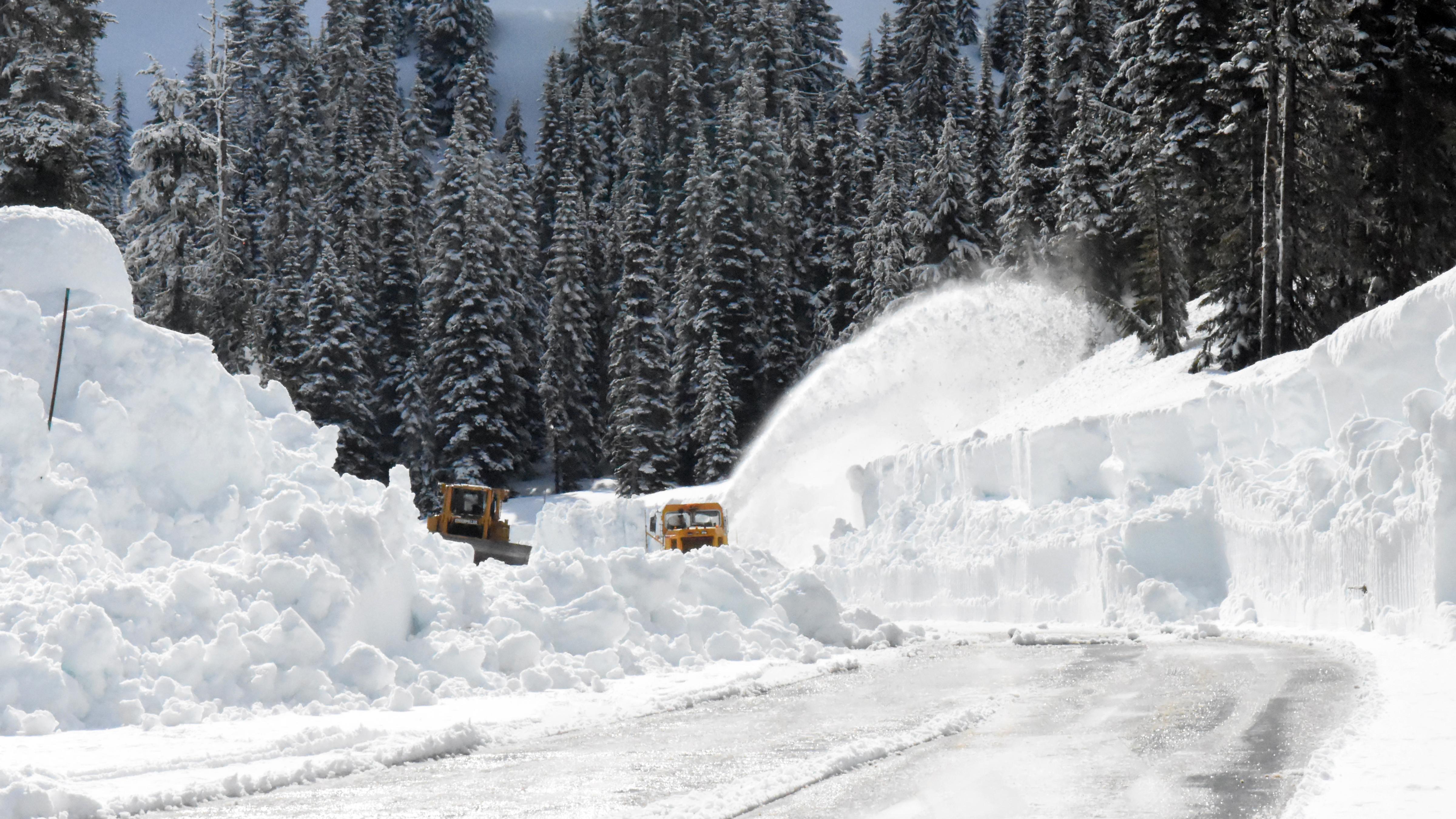 Two rotary plows clearing snow from a road.