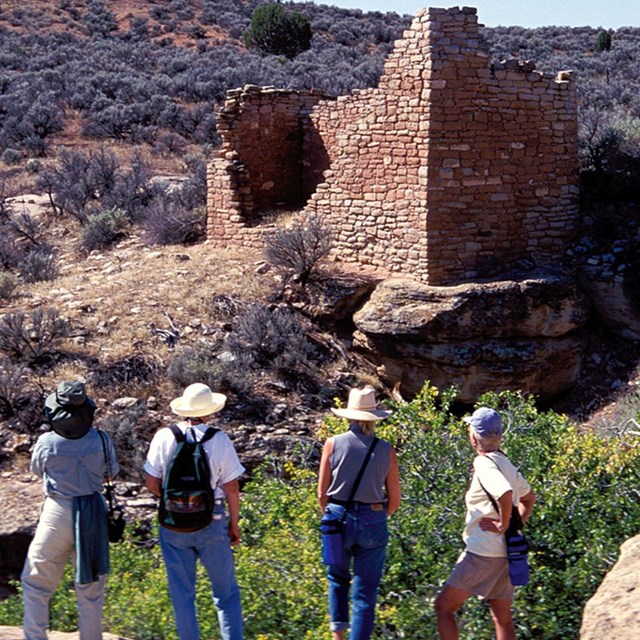 a group of people standing in front of a stone structure at Hovenweep