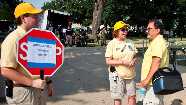 A volunteer showing visitors that the area is closed with a sign.