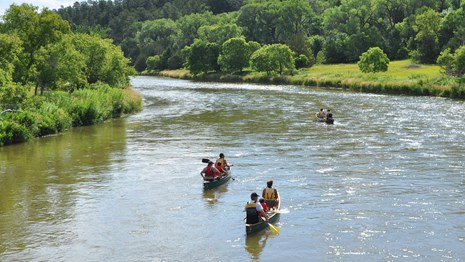 Canoes floating down the Niobrara National Scenic River on a sunny day. 