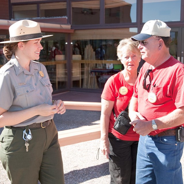 A ranger, in uniform, talking with two visitors