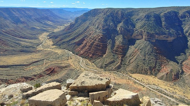 A wide desert canyon with sparse vegetation. 