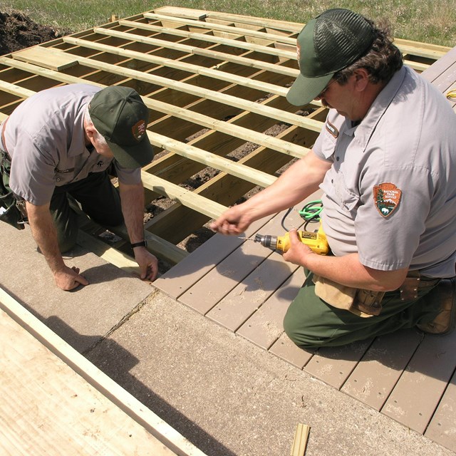 A photo of 2 maintenance men working on a deck