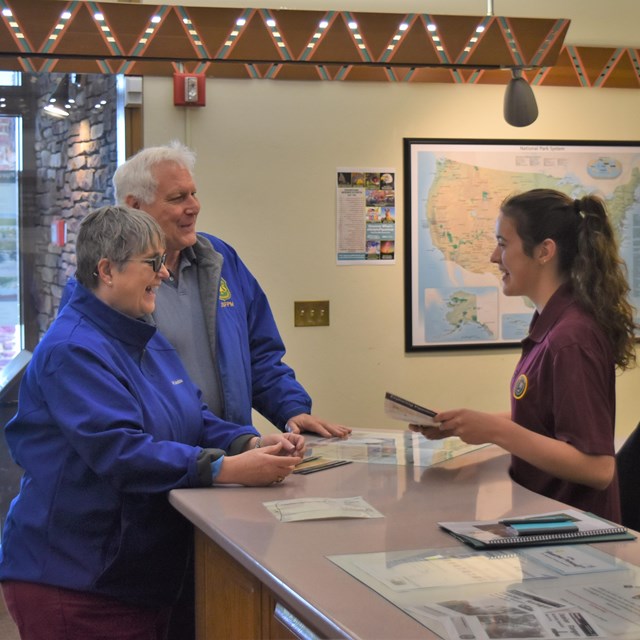 A volunteer at the front desk with 2 visitors