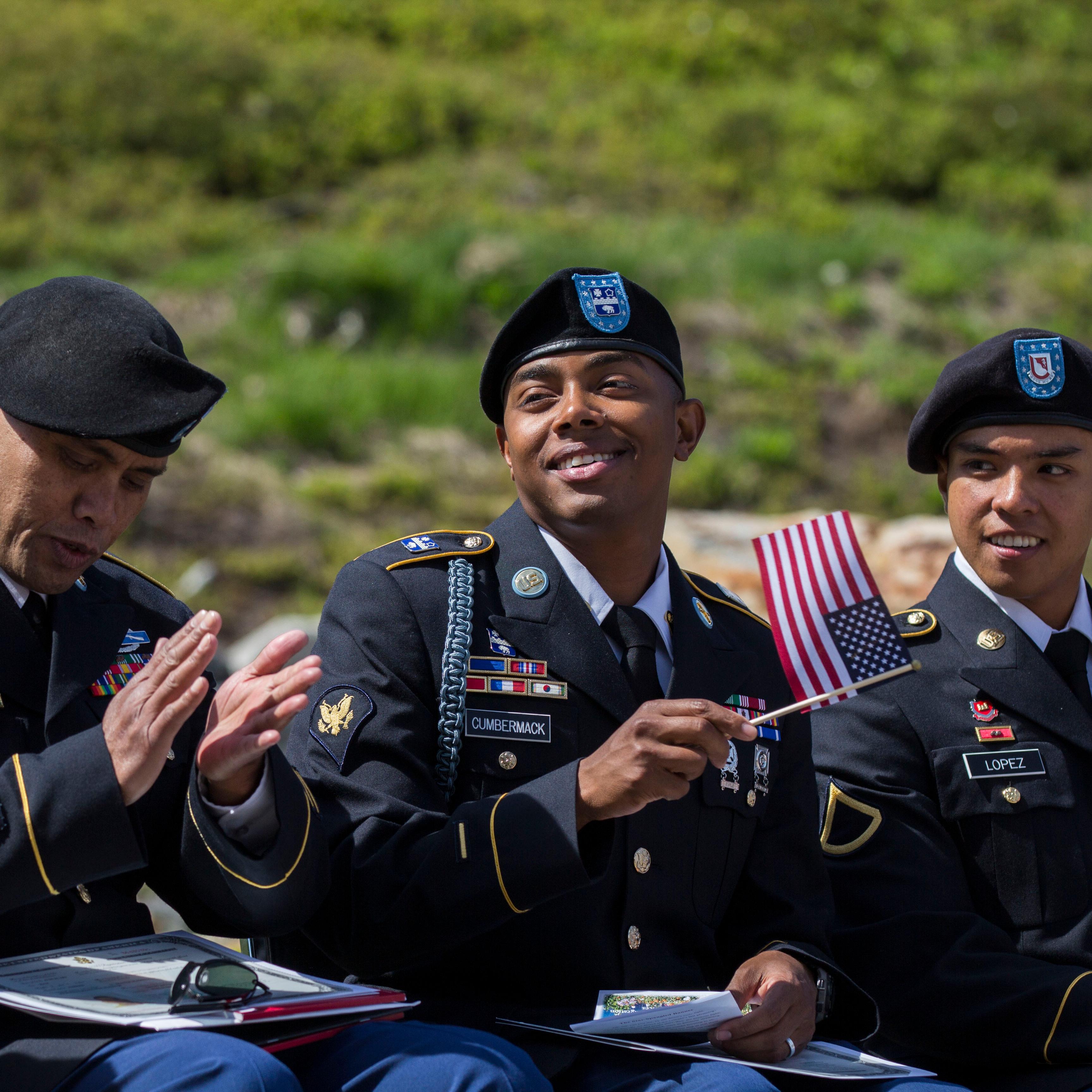 Three US military servicemen holding US flags