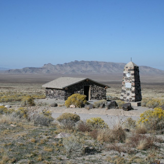 A stone building sits in an expansive desert setting.