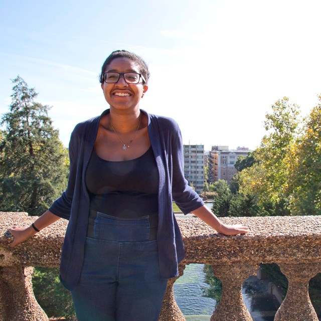 A young woman smiles as she stands on the top level of Meridian Hill Park. 