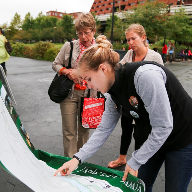 A young volunteer at Rock Creek Park shows visitors where they are on a map.