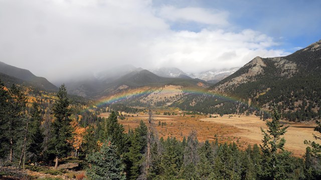 Clouds, rain, light snow, and a rainbow are seen over Horseshoe Park