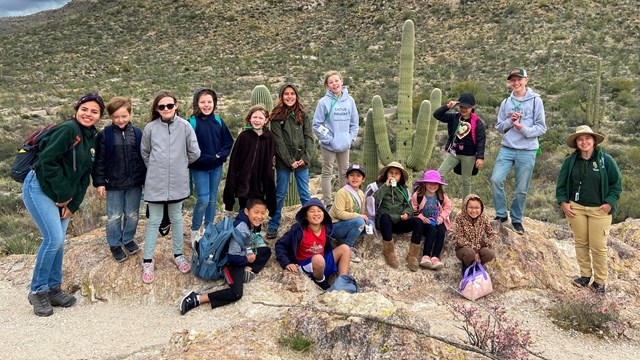 group of children and rangers on rock outcrop in desert landscape
