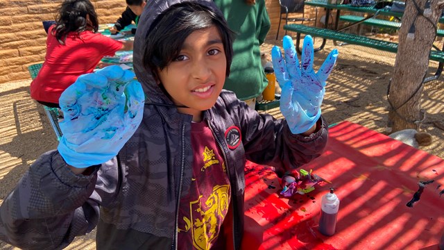 kid painting desert sunset colors in shade