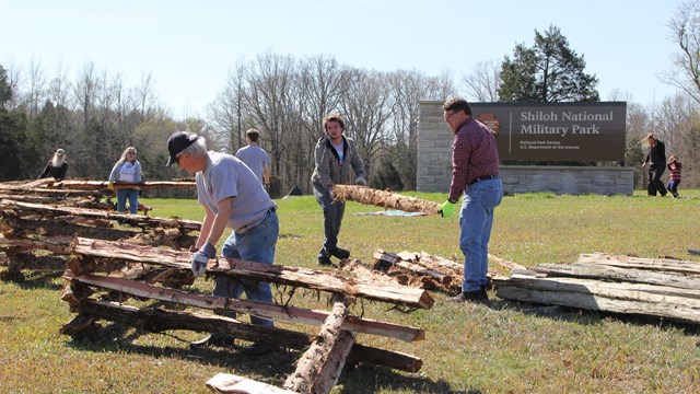 Volunteers erecting split rail fences in from of Shiloh entrance sign. 