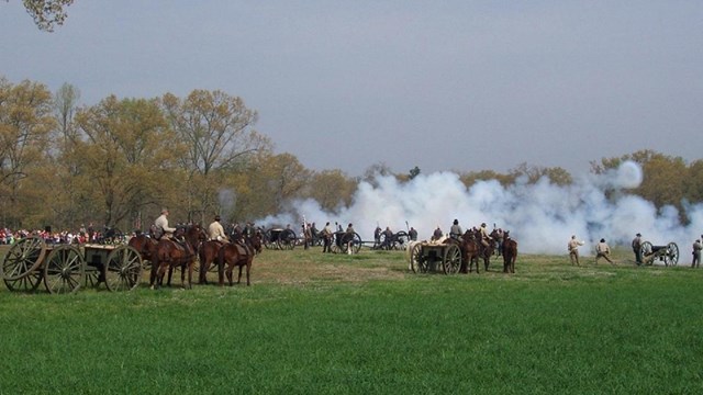 Smoke rises as living historians provide firing demonstrations for a crowd. 