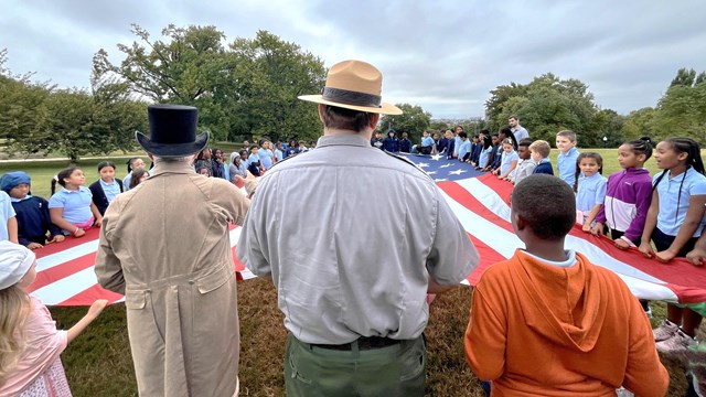 Visitors of all ages, holding the 30'x42' flag, with living historians and park rangers