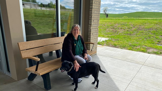 Visitor sitting outside the Visitor Center with their four-legged friend.