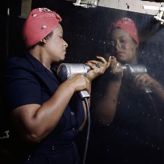 Woman riveting the side of a plane. 