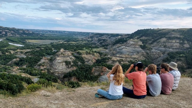 5 people look through binoculars. 