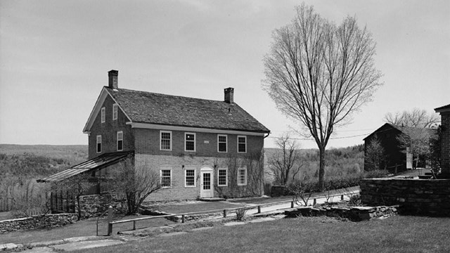 black and white photo of a brick building in a rural setting
