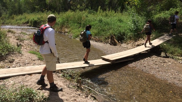 young hikers on plank bridge, spaced apart