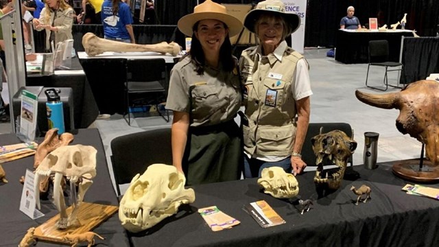 A park ranger and volunteer pose with fossil replicas.