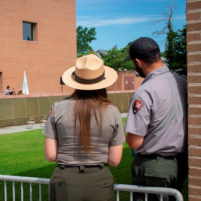 A female and male ranger face away from the camera and look out at Declaration Park