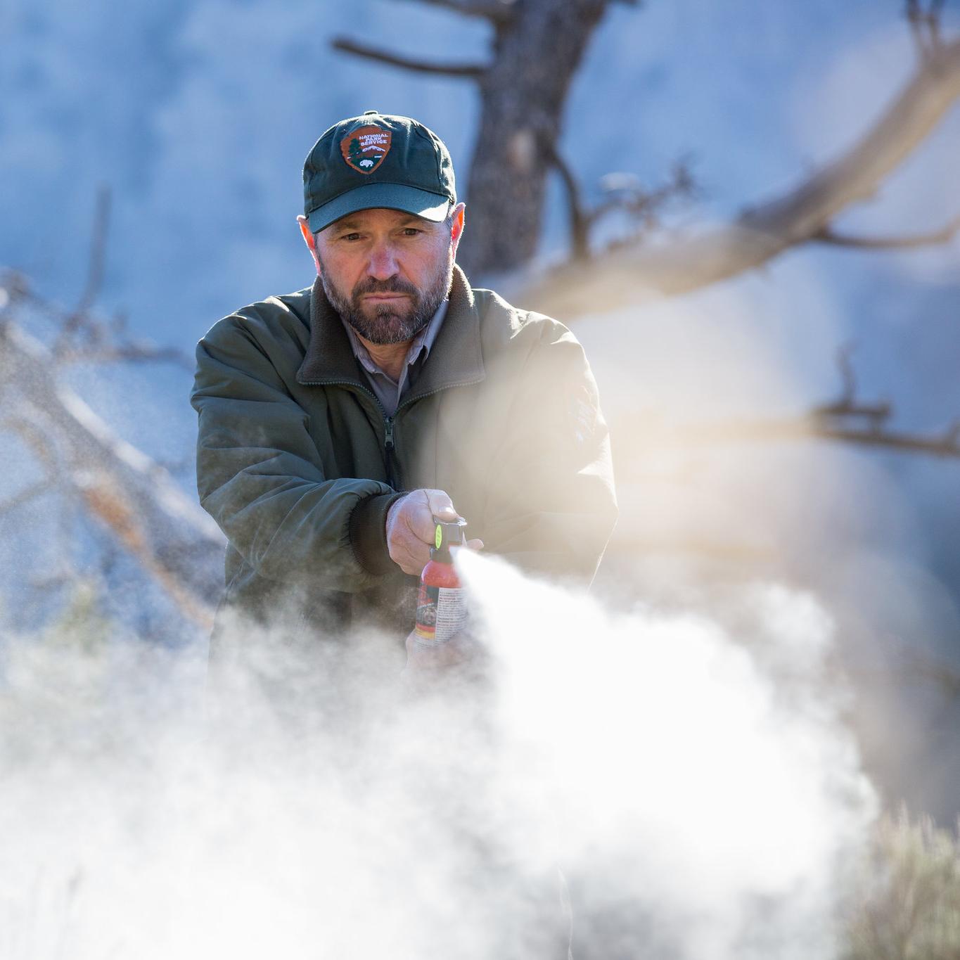 a park ranger spraying bear spray