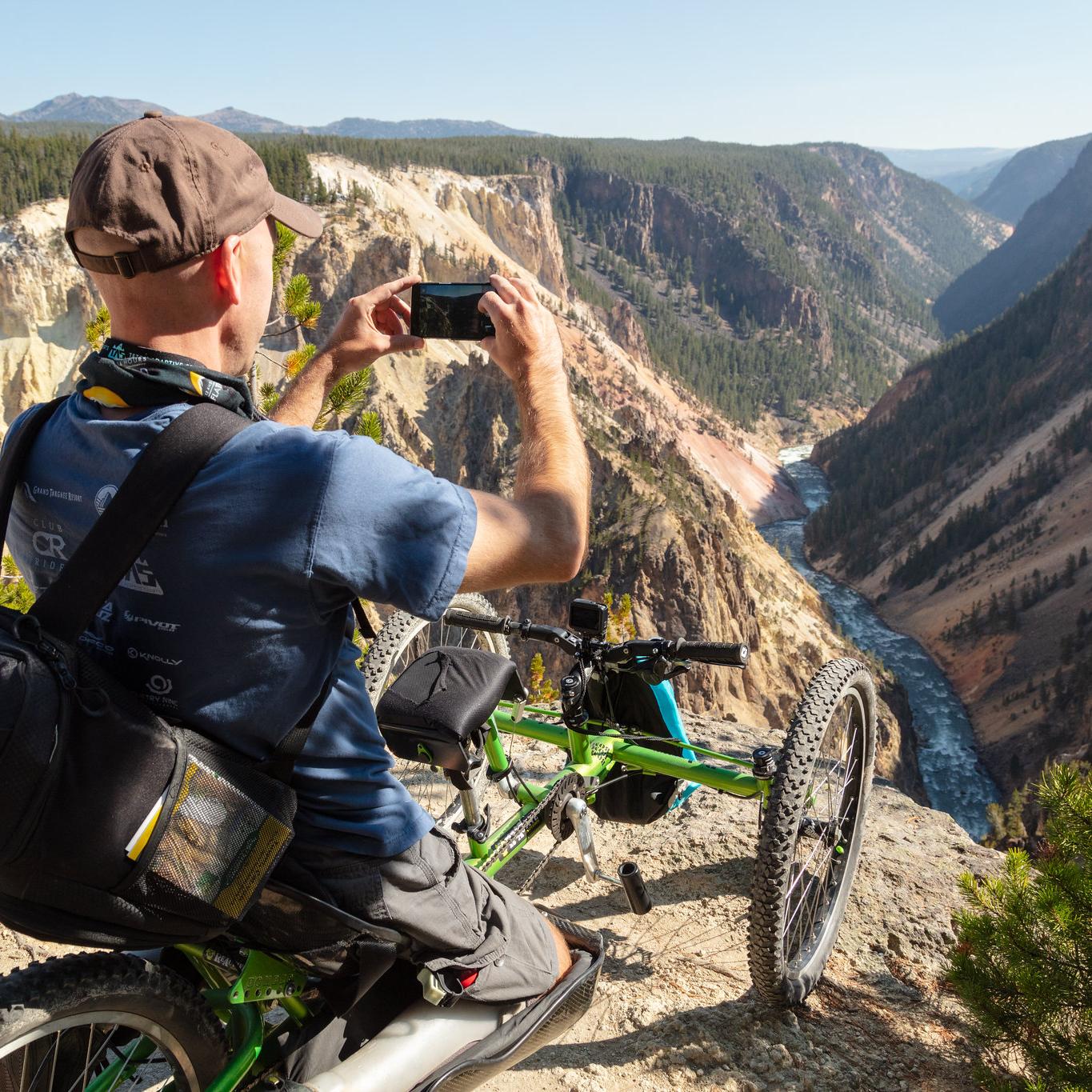 A person in a mobility chair photographs a canyon and river.