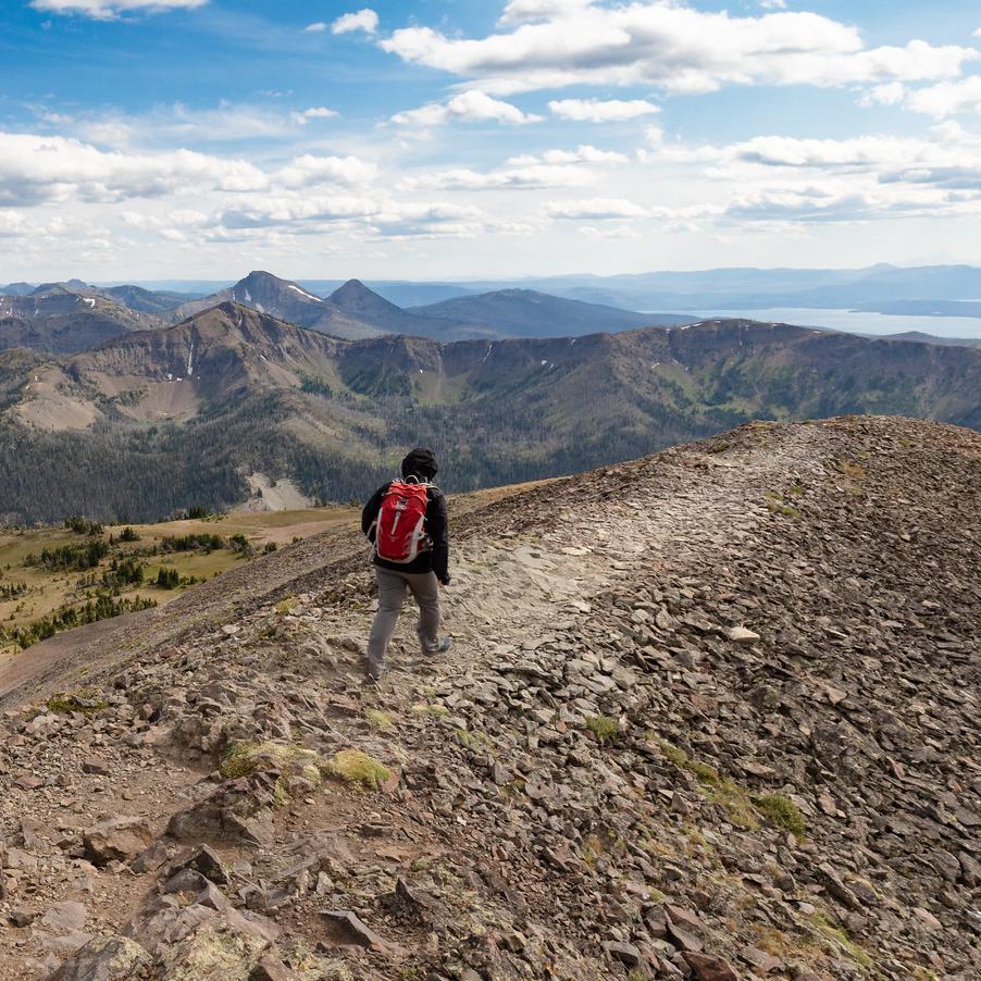 Hiker on a mountain ridge with a lake in the distance.