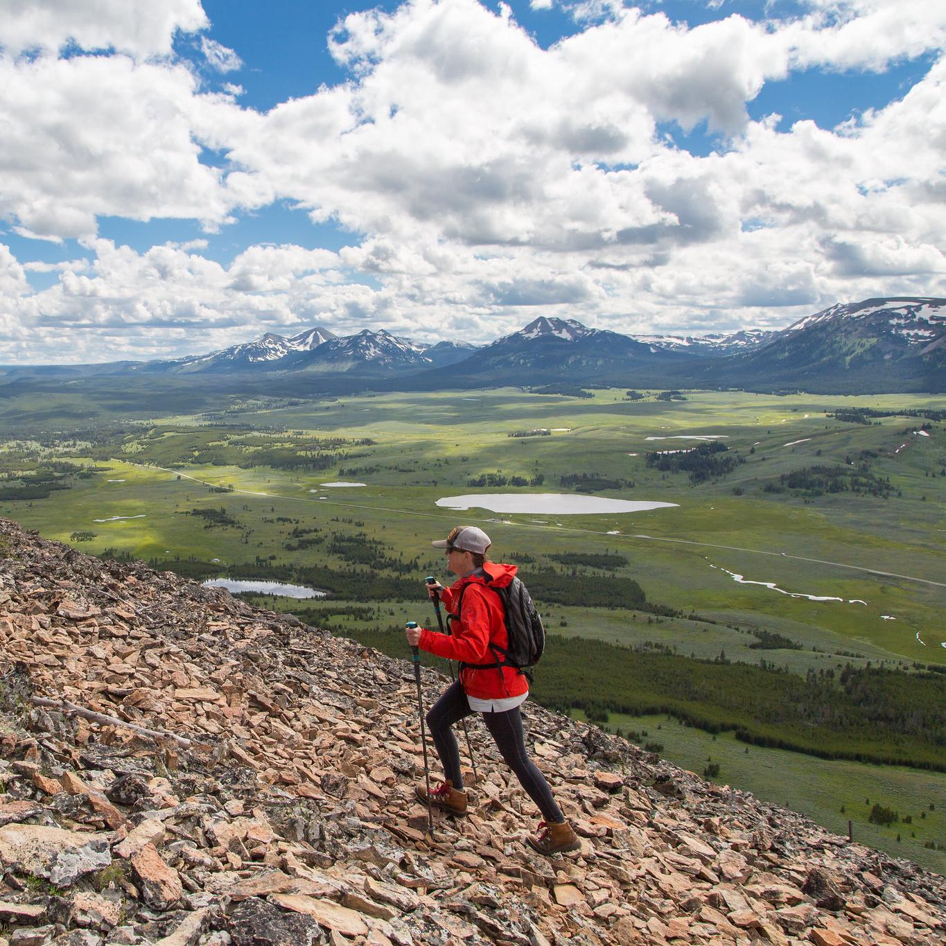 A person hikes up a trail with mountain views.