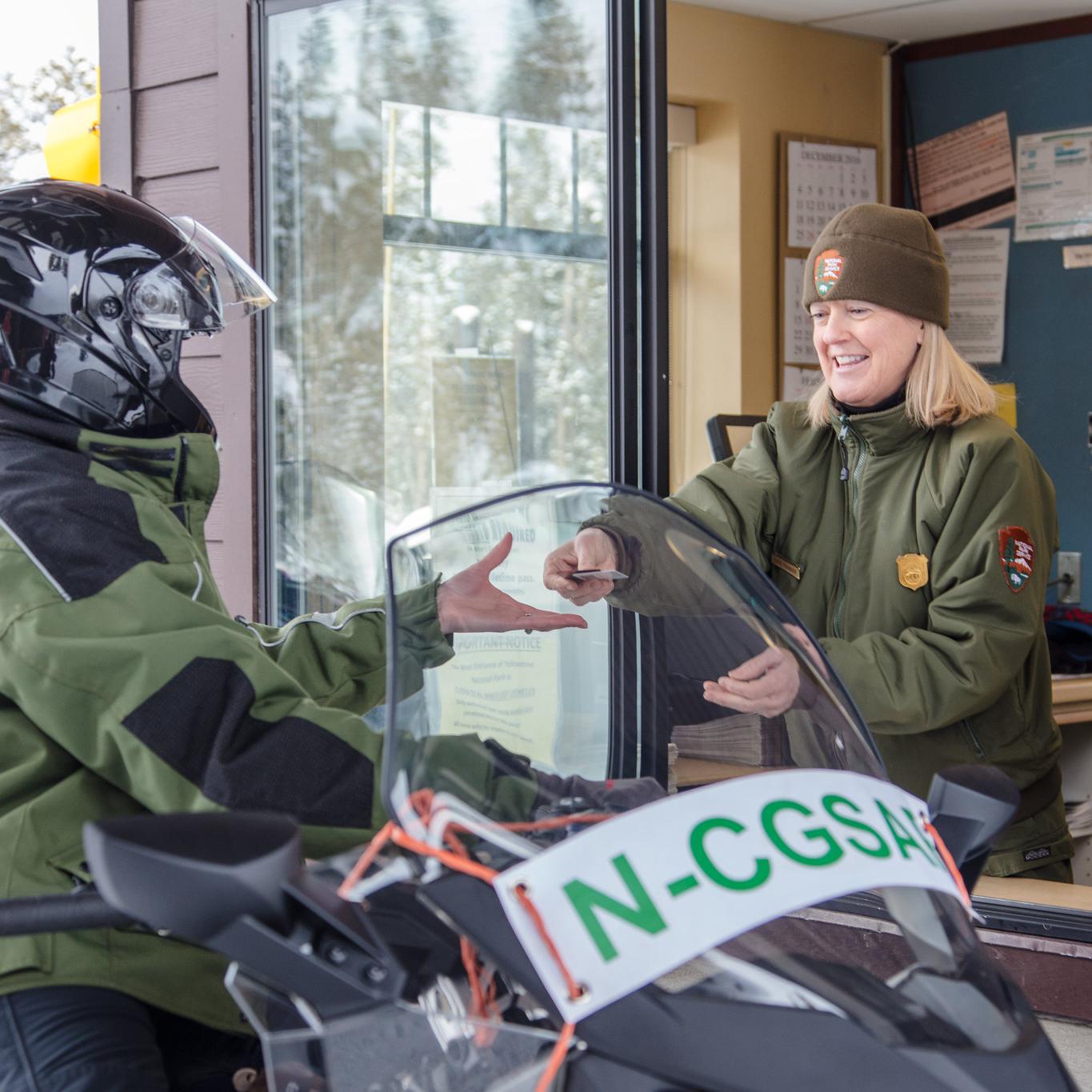 Visitors on a snowmobile talk with a park ranger