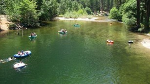 Visitors floating in rafts in the Merced River