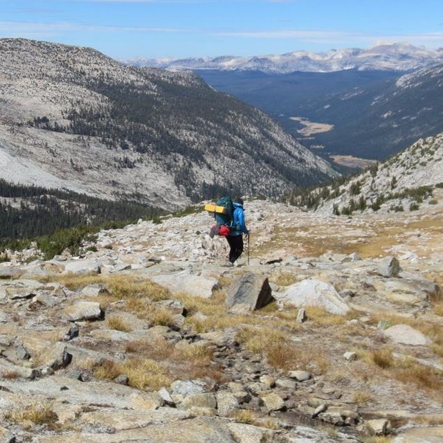 Hiker along Pacific Crest Trail just north of Donohue pass, rocky terrain