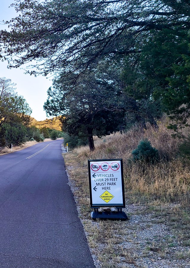 signs says to disconnect trailers and park vehicle over 29 feet here - trees behind