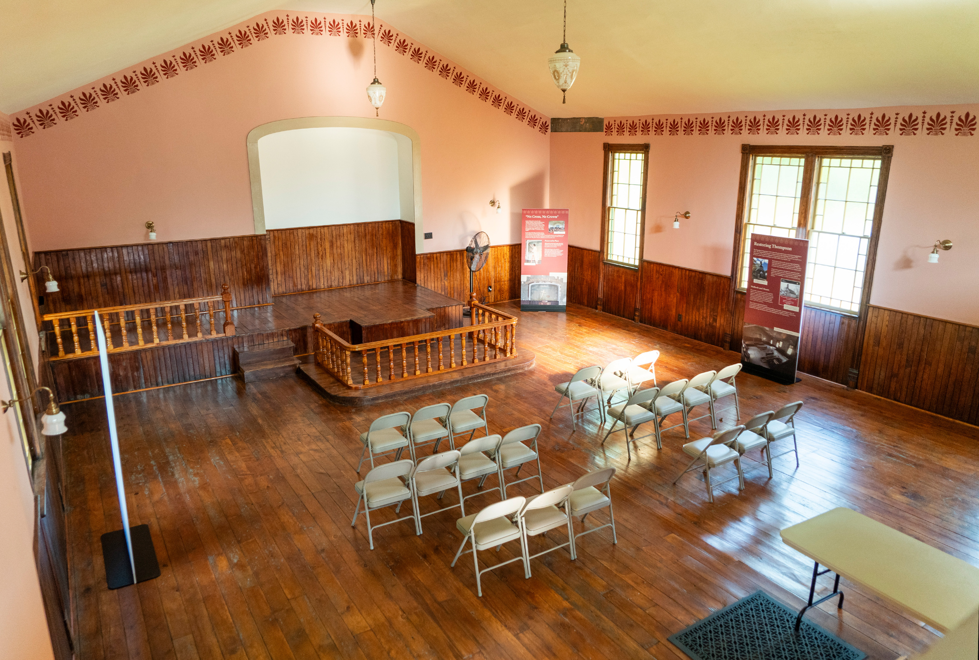 The interior of a run-down church, showing crumbling plaster, boarded windows, and construction materials.
