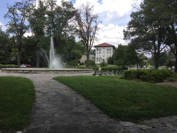 A circular fountain surrounded by benches and grass
