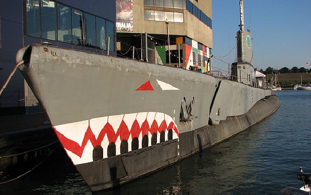 USS Torsk docked in water with painted shark face. 