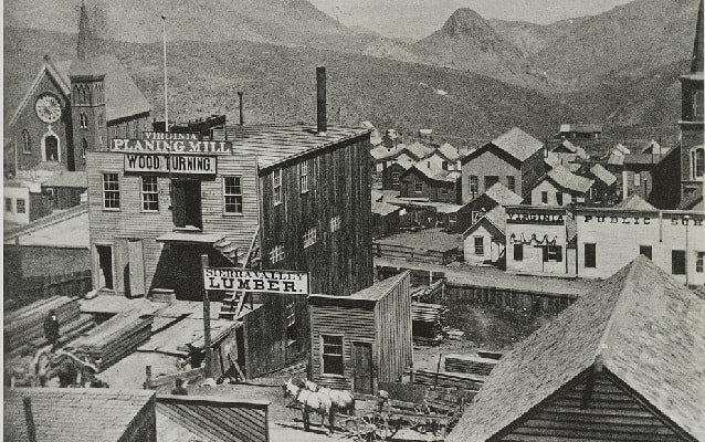 1866 photo showing birds eye view of old structures with mountains in background. 
