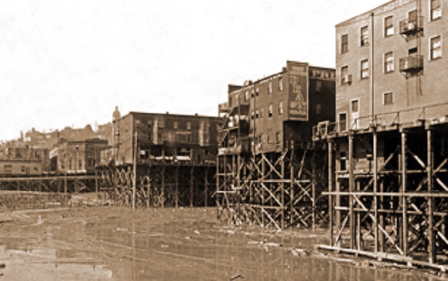 Black and white photo of buildings on stilts. 